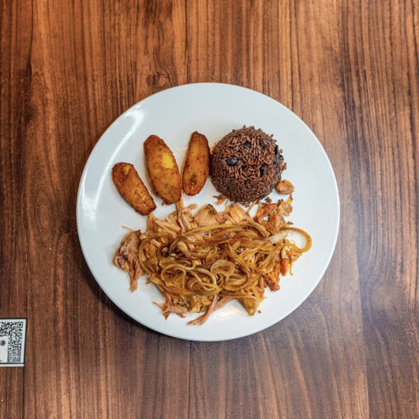 Cuban dish with shredded pork and onions, rice and beans, and fried plantains on a white plate.